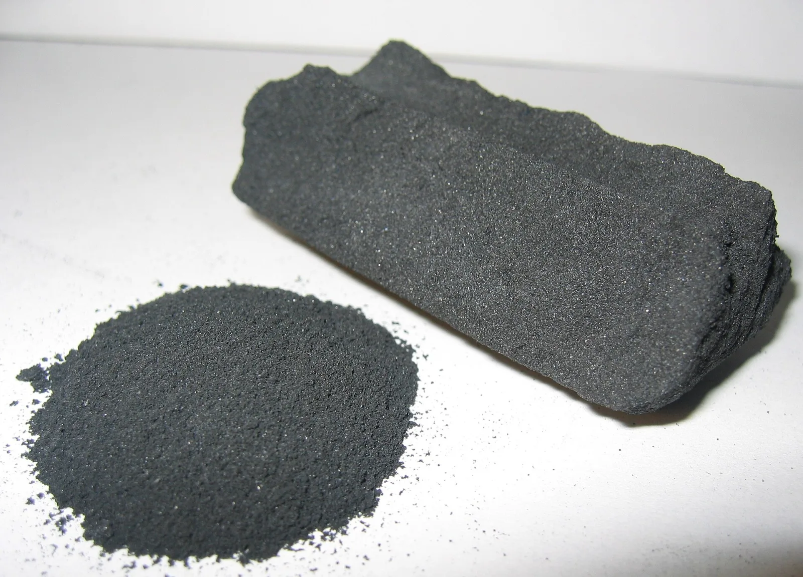 Activated carbon shown as loose black powder next to a solid carbon block